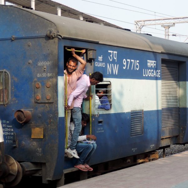 Men looking out from a train door as the train is at the platform, India