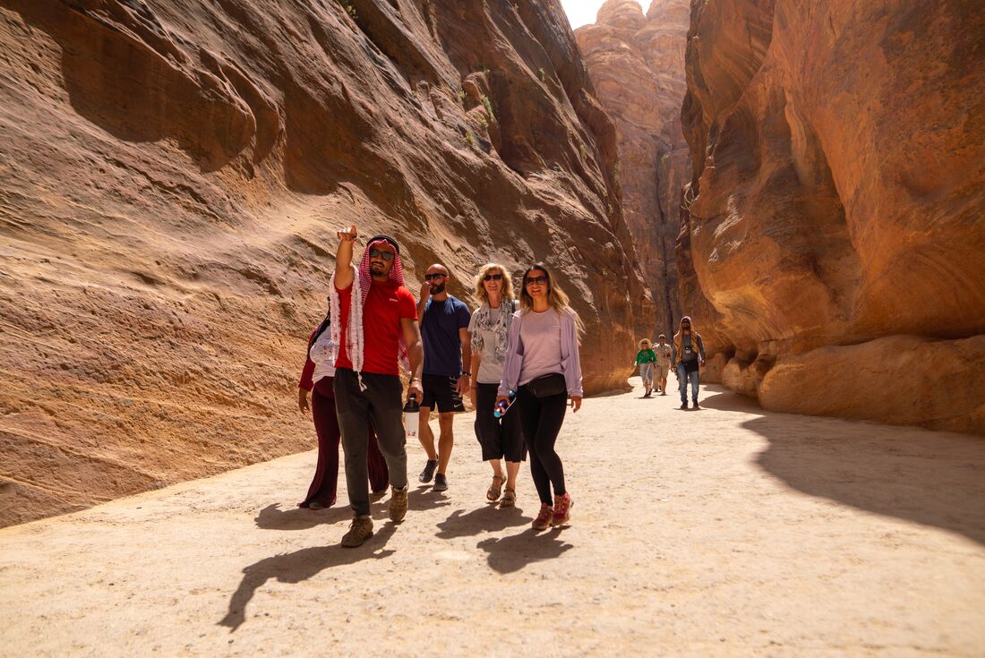Group led by Intrepid leader hiking in Petra as they approach Al-Khazneh in Jordan