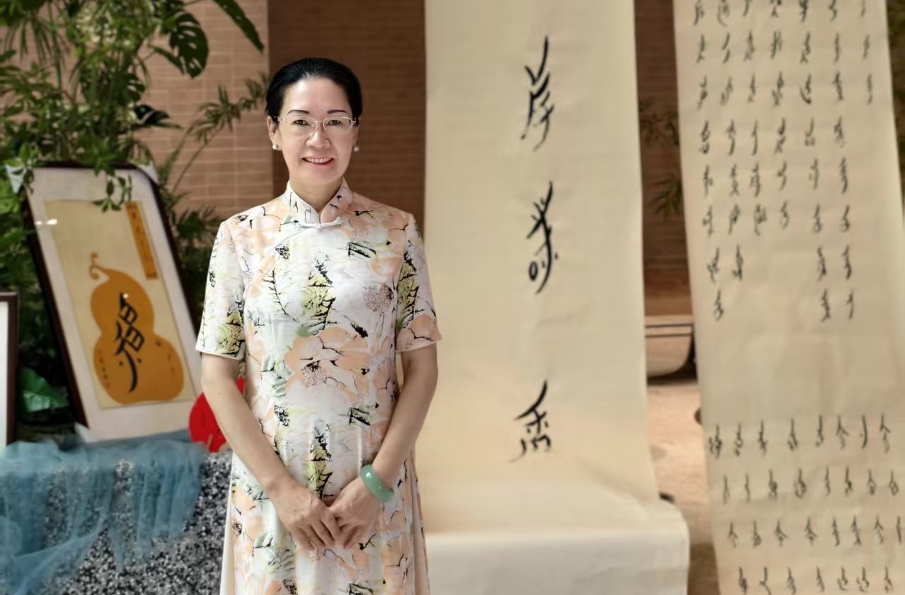 A woman standing in front of nushu script