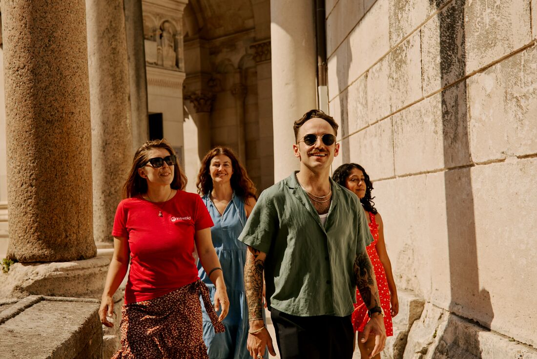 Traveller group and Leader smiling as they walk through Diocletian's Palace surrounded by cobblestone interior in Split, Croatia