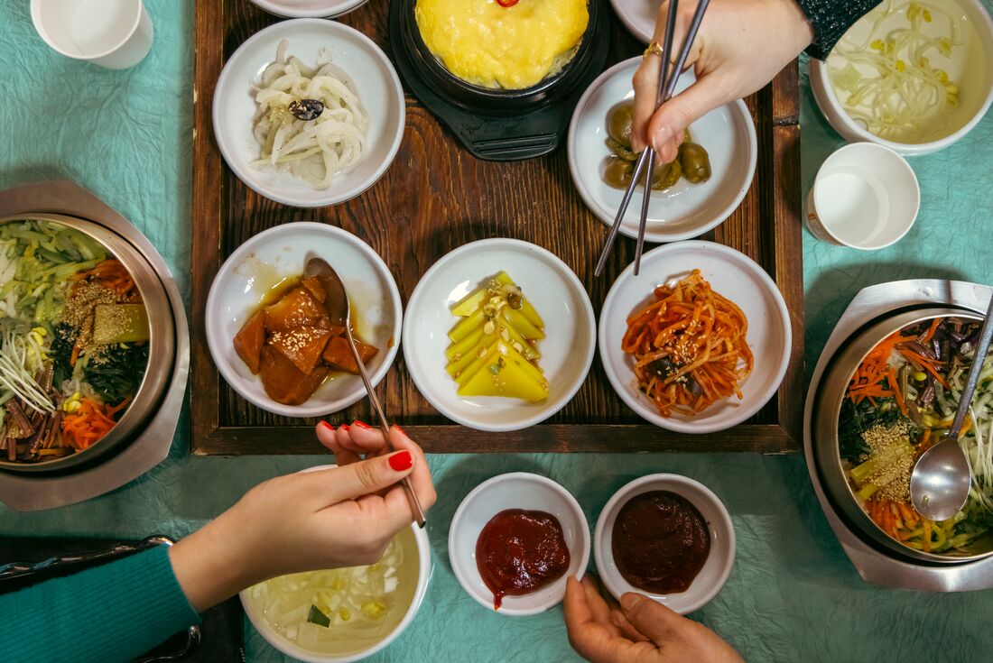 Top down look at travellers picking from Bibimbap lunch spread in Jeonju