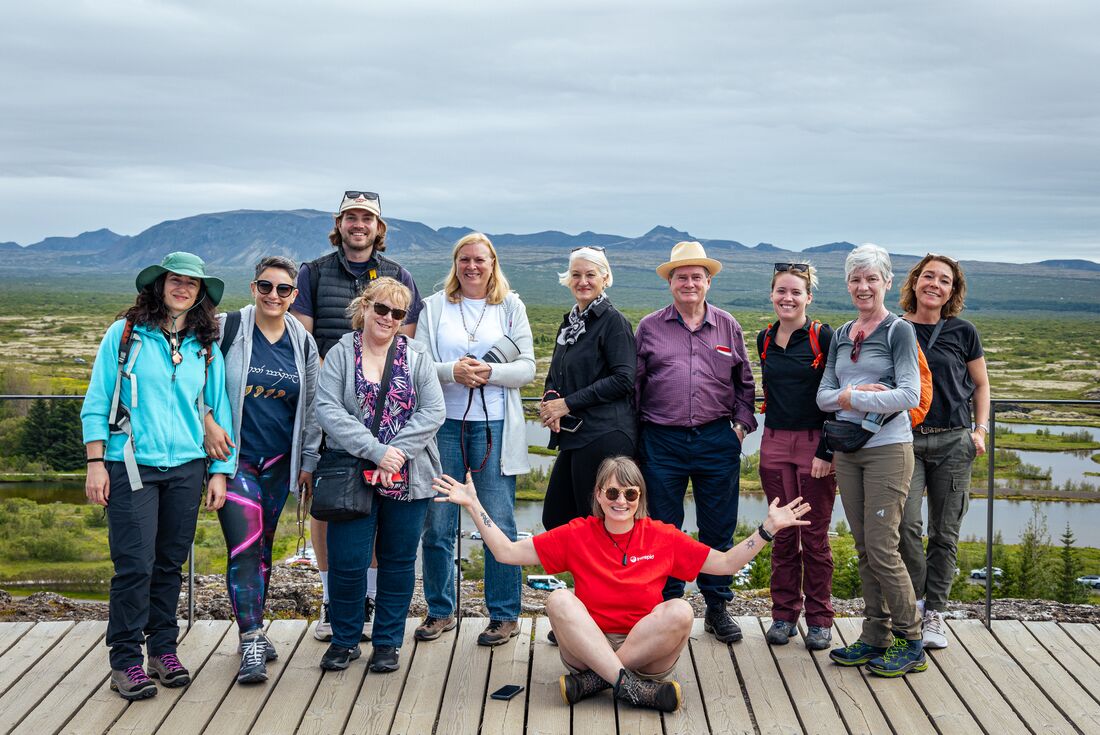 Group of Intrepid travellers pose for a group photo in front of the greenery in Thingvellir National Park