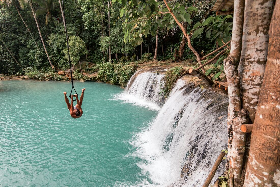 Intrepid traveller on a rope swing into Cambugahay Falls on Siquijor island in the Philippines