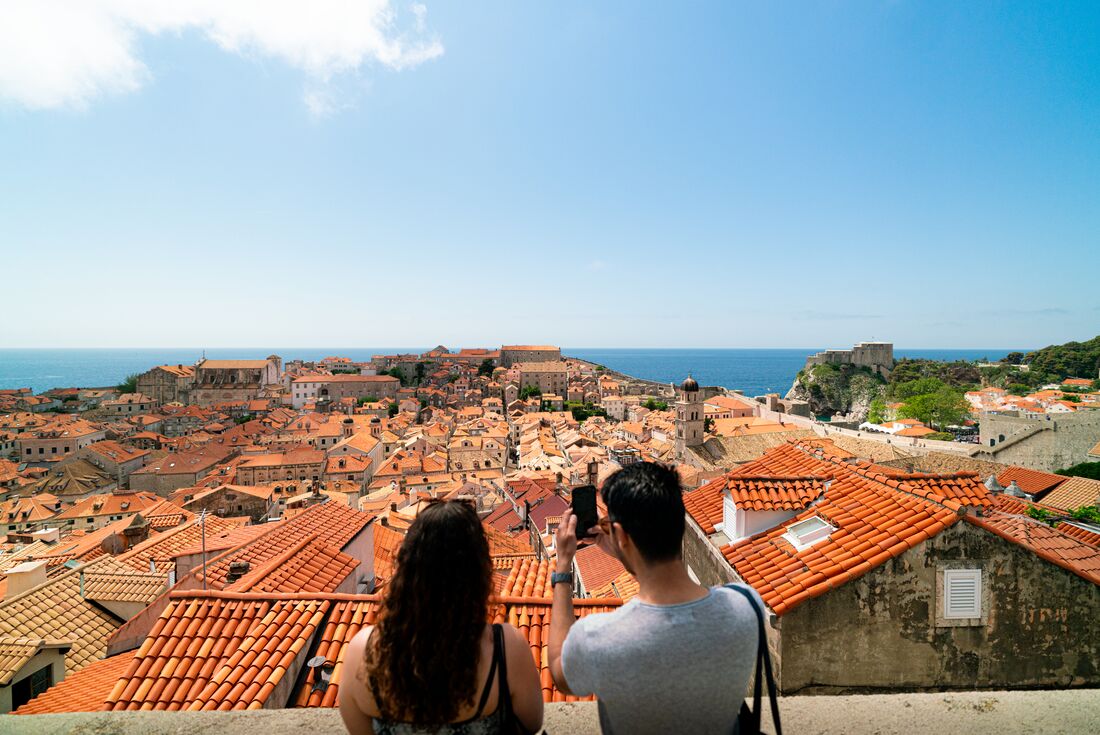 Travellers looking out over Dubrovnik Old Town taking photos 