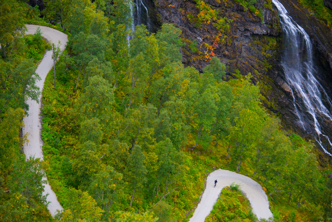 Intrepid travellers cycles the winding Rallarvegen road Myrdal to Flam with waterfalls nearby in Norway