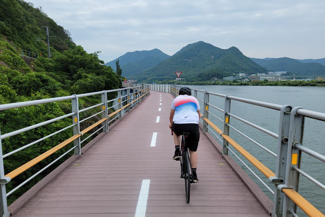 Traveller cycling on the 4 Rivers Bike Trail on a suspended bike path over the waters of the Han River in South Korea