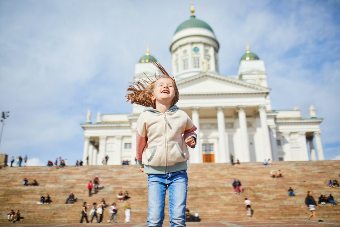 Intrepid traveller child jumps happily in Helsinki square in Finland