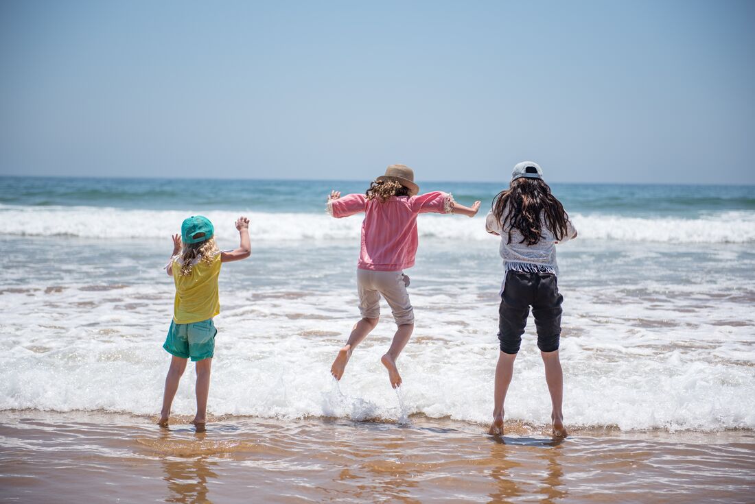 Children enjoy jumping in the waves at the beach at Essaouira in Morocco