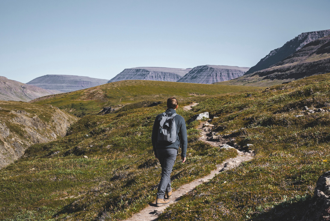 Male traveller hikes toward plateau mountain tops in western Greenland toward Lingmark Glacier