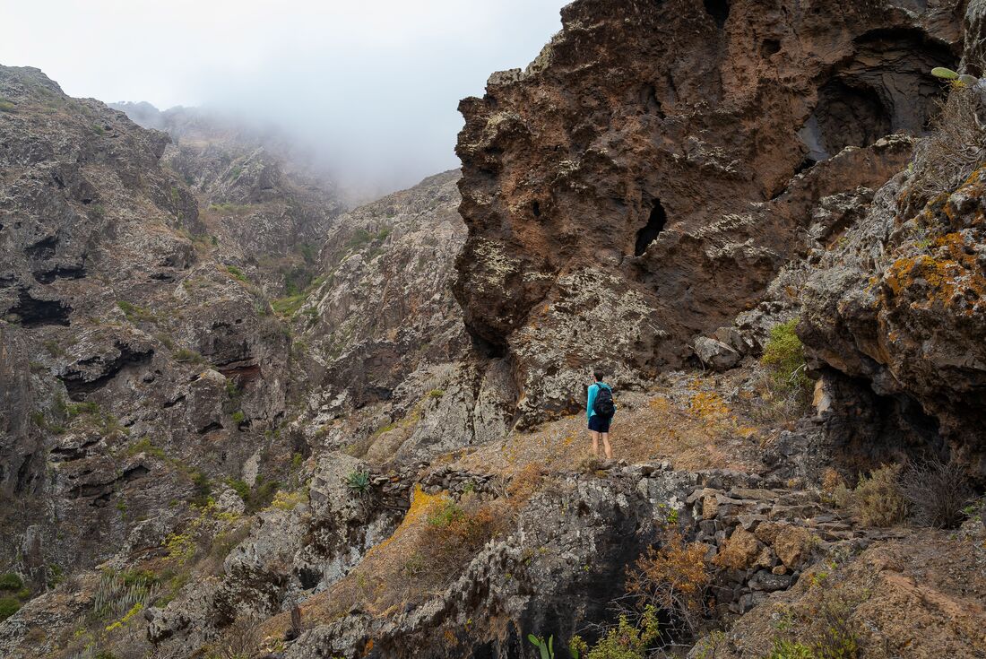 Travellers looks up at the surrounding mountains while hiking in Teno Rural Park in Tenerife