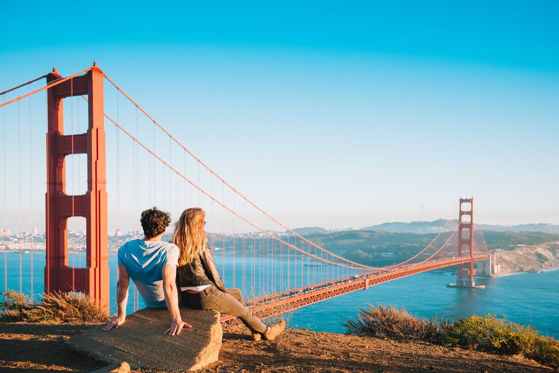 Two travellers in Golden Gate Park look out across the bridge and bay at San Francisco in California USA