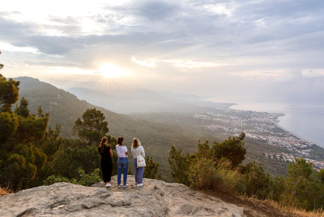 Womens expedition travellers look out on Adatepe from a cliff at the Altar of Zeus in Turkiye