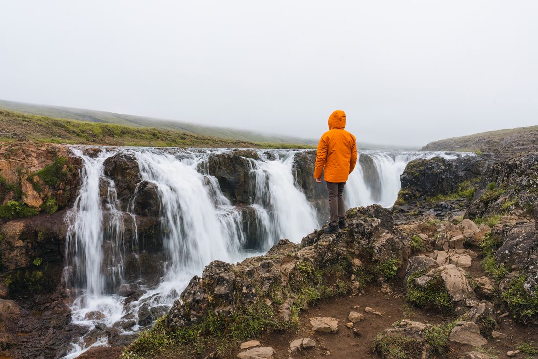 Traveller standing near precipice of Kolugljufur canyon waterfalls in Iceland