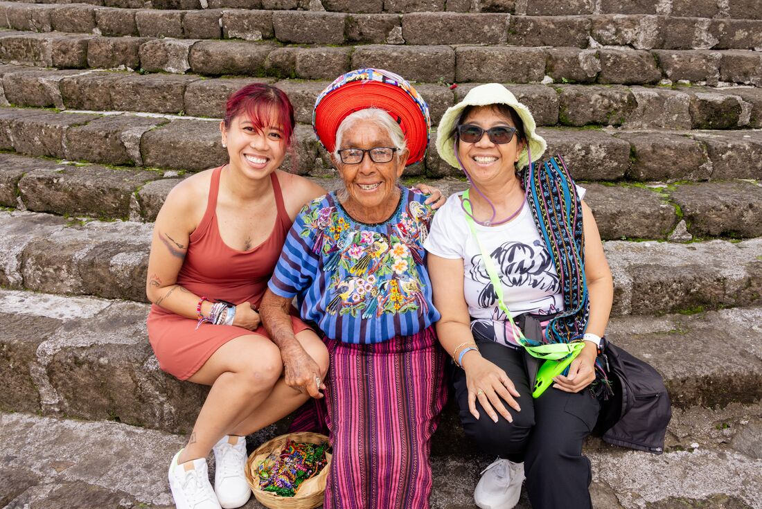 Intrepid travellers sit with a kindly local woman on the streets of Santiago Atitlan's main church in Guatemala