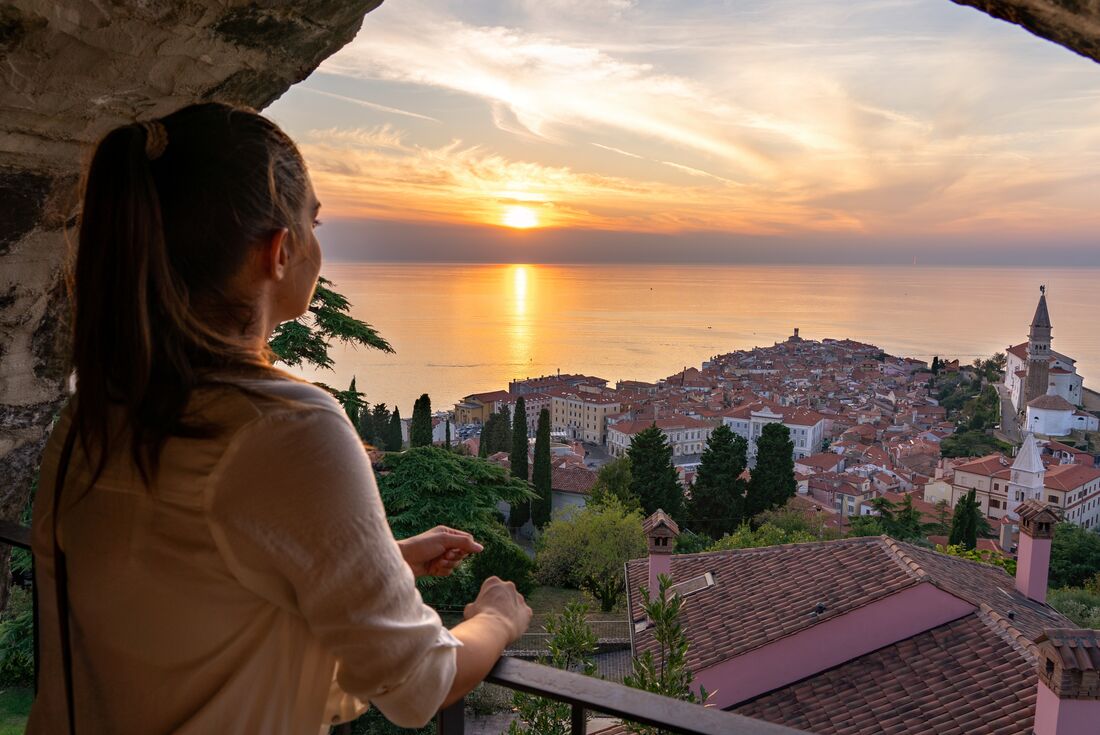 Teenage traveller looking out over Piran in Slovenia at sunset